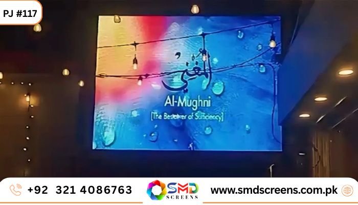 Indoor SMD screen displaying “Al-Mughni (The Bestower of Sufficiency)” with colorful abstract background — Project #117 by SMD Screens Pakistan.