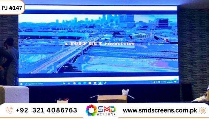 A large indoor LED screen displays a cinematic scene of a cityscape, bridge, and river, with the text "A TOFF GUY PRODUCTION."