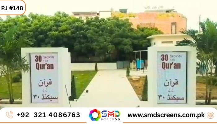 Two matching vertical outdoor LED screens mounted on white pillars at the entrance of a building, displaying "30 Seconds for Qur'an" in English and Urdu.